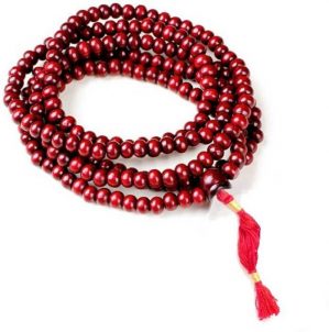 It's a photo of Dark red connected pearls of red sandalwood (MALA) are strings together through the cotton thread which is unitedly become prayer's "MALA", is placed on plain white background in a folded form.
